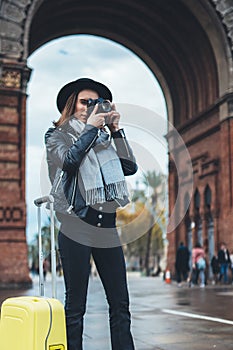 Photographer tourist with retro photo camera. Girl in hat travels in Triumphal arch Barcelona. Holiday concept street in europe