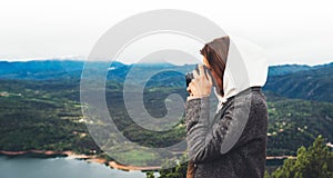 Photographer tourist traveler standing on green top on mountain holding in hands digital photo camera, hiker taking click photogra