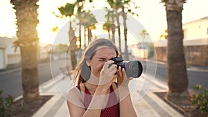 Photographer tourist woman taking photos with camera in a beautiful tropical landscape at sunset