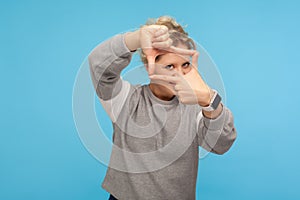 Photographer view. Curious woman pretending to take picture, focusing on camera through photo frame hand gesture