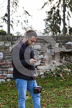 Photographer with vintage analogue film camera and smartphone outdoors