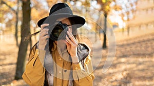 Photographer woman taking a photo outdoor traveling in autumn forest