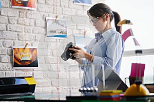 Photographer Working And Checking Digital Camera Settings In Office