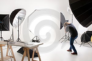 Photographer working in modern lighting studio with many kinds