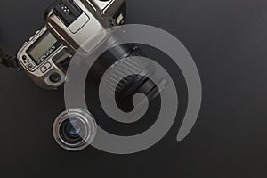 Photographer workplace with dslr camera system and lens on dark black table background. Hobby travel photography concept. Flat lay