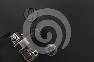 Photographer workplace with dslr camera system and lens on dark black table background. Hobby travel photography concept. Flat lay