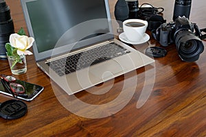 Photographer workplace with laptop, camera, lenses, coffee cup and phone on a wooden table,  copy space