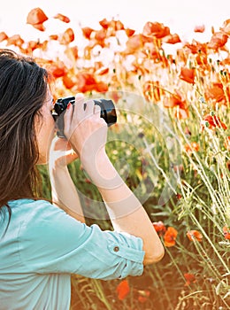 Woman taking photographs with camera in meadow.