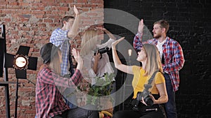 Photographers giving high five to each other after a successful masterclass with cameras in hands on the background of a