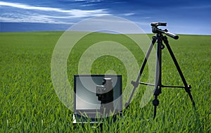 Photographic equipment and laptop on a green field