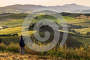 Photographing Tuscany landscape with traditional farm house, hills and meadow at sunrise. Val d`orcia, Italy.