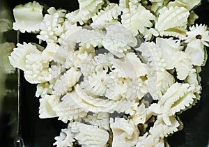 a photography of a black bowl filled with chopped up cauliflower, coral reefed cauliflower in a black container on a table