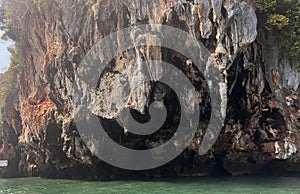 a photography of a boat in the water near a rock formation, drop - off of a boat in the water near a rocky cliff