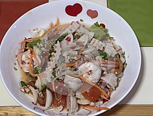 a photography of a bowl of food with a heart shaped decoration, plate of food with meat, vegetables, and sauce on a table