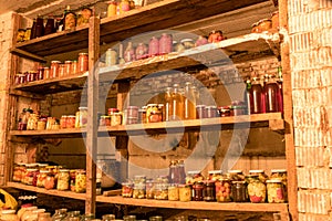Photography with canned jars in the basement of the house, jars of different shapes on wooden shelves, various canned food, autumn