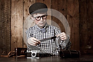 Photography, child and vintage with camera film, thinking and mockup in glasses by backdrop. Boy, idea and nerd with