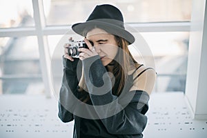 Photography hobby. Stylish ypung photographer girl in black hat. Soft backlight