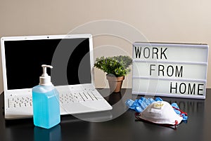 Photography of a home desktop during coronavirus quarantine and a light box with a message and medical ppe protections.