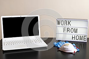 Photography of a home desktop during coronavirus quarantine and a light box with a message and medical ppe protections. Remote