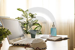 Photography of a home office with a laptop on the desk and some medical ppe while teleworking