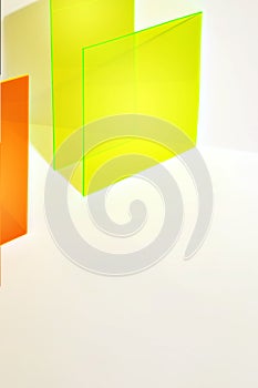 Photography of an orange and neon yellow acrylic sheet with shadow on white background.