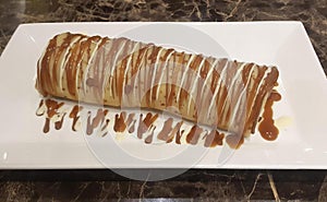 a photography of a plate with a pastry covered in caramel sauce, there is a long pastry with caramel sauce on a plate