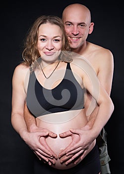 Photography pregnant woman with her husband in the studio in different positions hugging her from behind