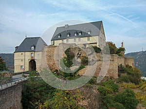 Photography of the ruins castle walls and castle buildings of Ebernburg in light cloudy sky. Some plants entwine on the castle