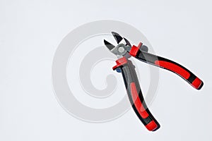 Photography of silver metal pliers with red and black rubber grips