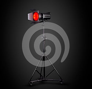 Photography studio flash on a lighting stand isolated on black background.