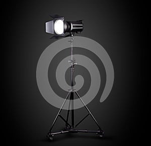 Photography studio flash on a lighting stand isolated on black background.