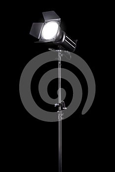 Photography studio flash on a lighting stand isolated on black background.