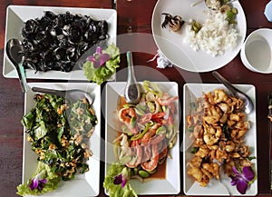 a photography of a table with four plates of food and a bowl of rice, plate of food on a table with a variety of dishes