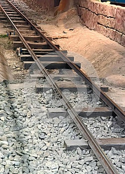 a photography of a train traveling down train tracks next to a tunnel, freight car on tracks in a tunnel with rocks and gravel