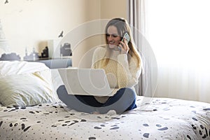Photography of a woman teleworking in her bed from home talking on the phone. Coronavirus quarantine. Remote working woman
