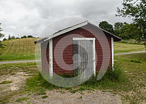 Photography of a wooden red house and a road in a field in the mountain in sweden photo