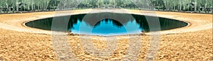 Photomontage of a turquoise lake as a circle with a beach of yellow sand at the end of the summer