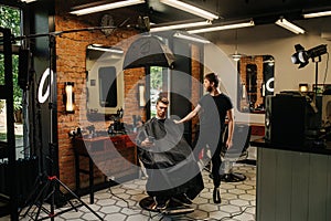 Photosession in a barber shop. Client in a chair, hairdresser next to him