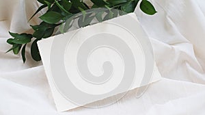 Photostock wedding styled composition. Feminine envelope mockup scene with ruscus leaves, silk ribbon, blank greeting card, envelo