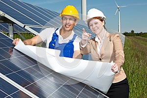 Photovoltaic engineers with construction plan at solar panels