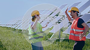 At photovoltaic solar farm happy and excited ecological engineers jumping up after they end the work they wearing safety