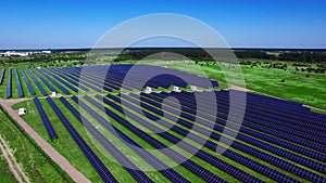 Photovoltaic solar panels on green field at sunny day. Aerial landscape