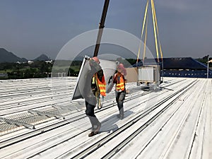 The Photovoltaic solar panels transported by the Crane trucks and workers at the rooftop
