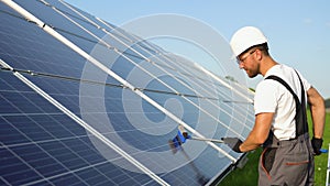 Photovoltaic technician cleaning and washing the surface of the solar panels