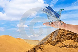 Photovoltaics solar panels in shopping trolley cart on women hand in desert.