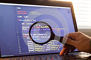 PHP back-end code zoomed through a magnifier. Computer programming source code lookup. Abstract screen of web developer photo