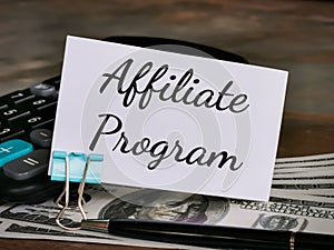 Phrase Affiliate Program written on white card with calculator,paper clip,fake money and a pen.