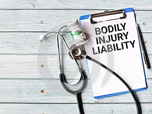 Phrase bodily injury liability written on paper clipboard with a pen,stethescope and fake money.