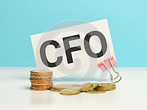 Phrase CFO written on white card with coins.
