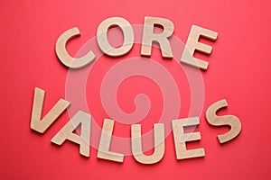 Phrase CORE VALUES made of wooden letters on red background, flat lay